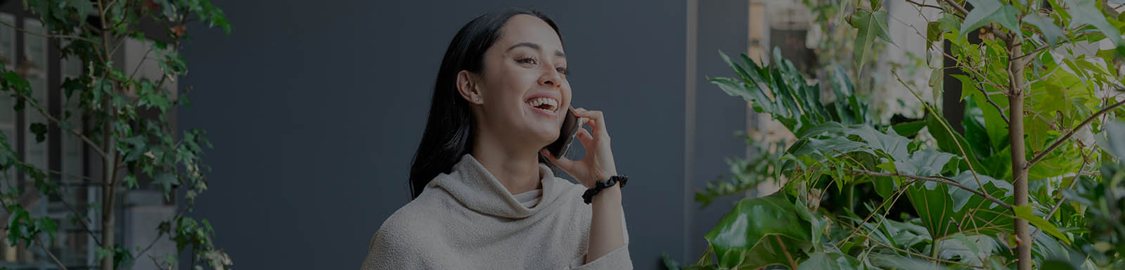 A woman standing near the garden area and smiling while talking on phone