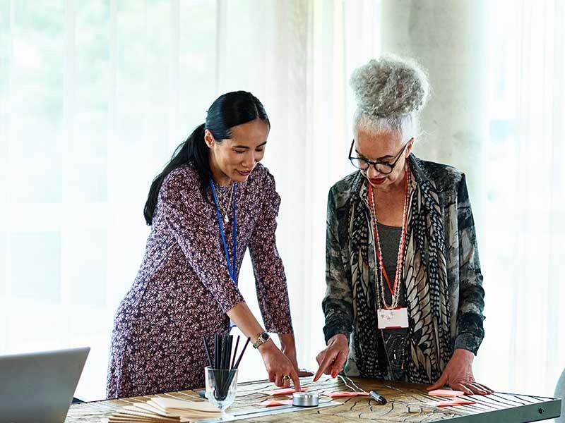 Two Businesswomen brainstorming in an office using adhesive notes before the meeting