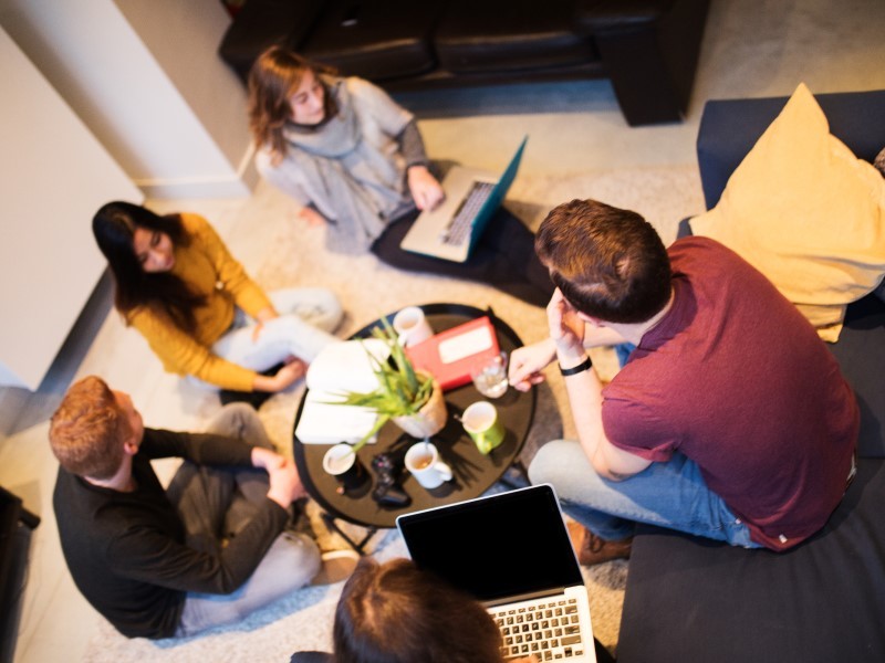 A group of diverse people having coffee and living in a  coliving space